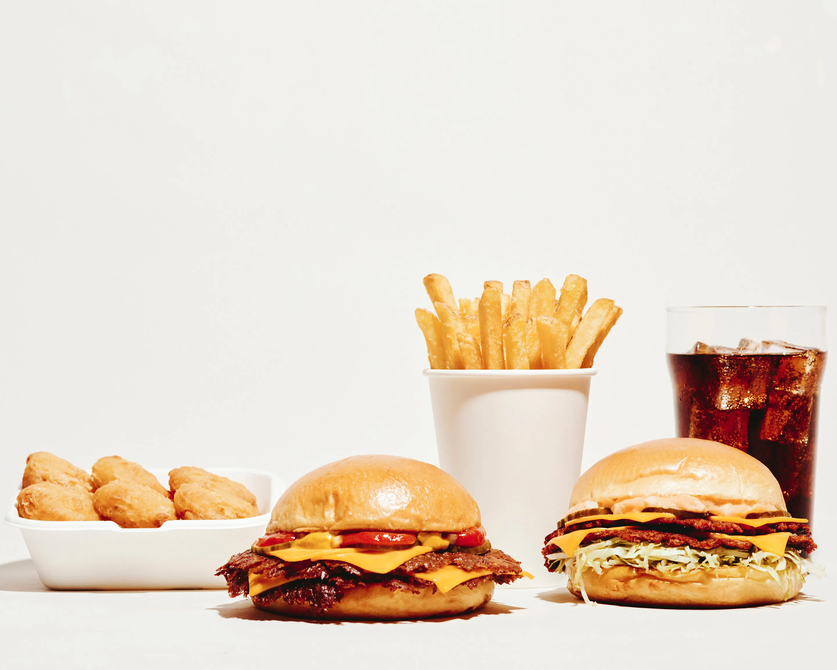 La gamma Dumbo su fondo bianco: nuggets, due cheeseburger, un cono di patatine e una coca ghiacciata