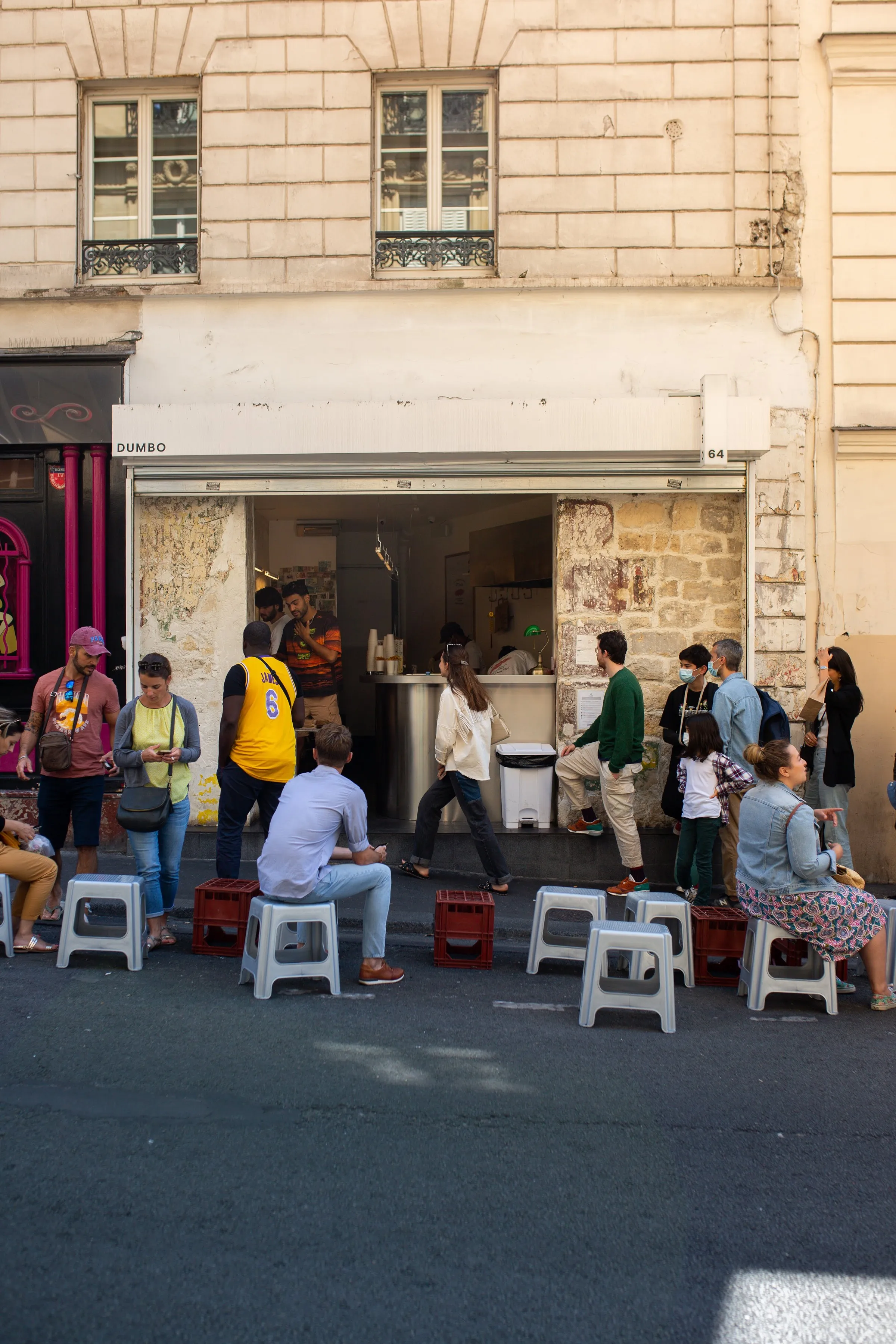 Rue Jean-Baptiste Pigalle: people eating on stools and crates along the street outside Dumbo